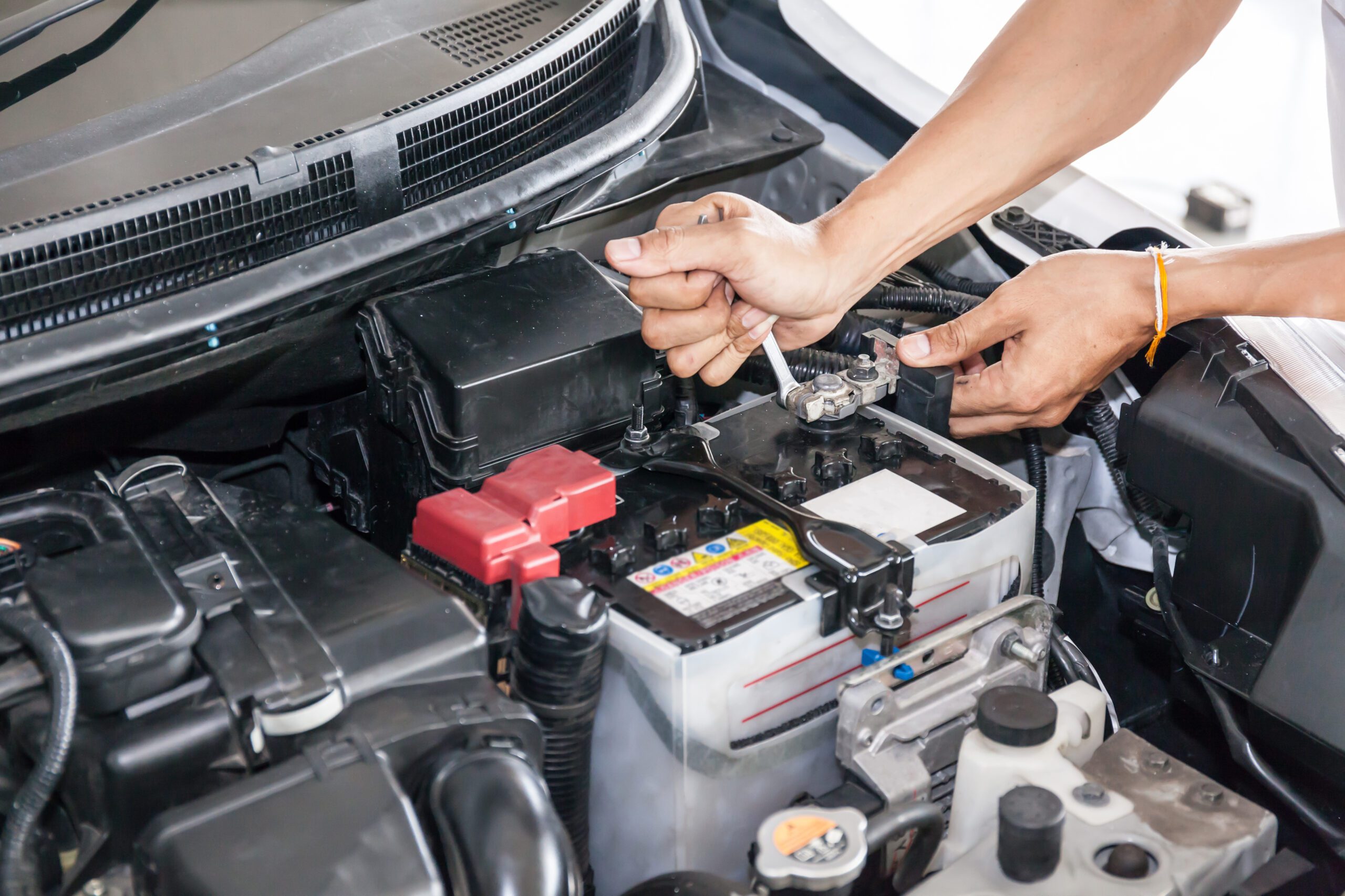 Mechanic engineer fixing car battery in garage (selective focus)